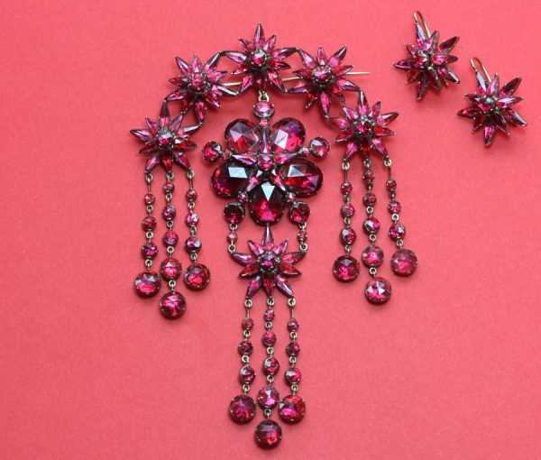 Antique Georgian Garnet and 18ct Gold Demi Suite; star earrings, cross pendant and large devant de corsage brooch, set with rose-cut garnets, Circa 1865.