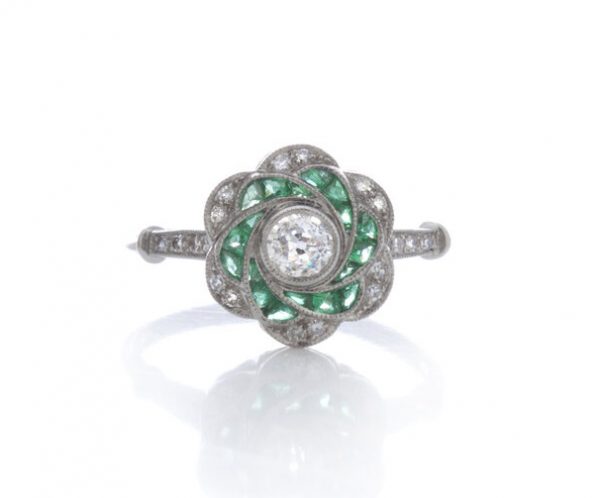 Vintage Emerald and Diamond Flower Swirl Cluster Ring; central old cut diamond surrounded by calibre cut emeralds and round old-cut diamonds. Mounted in 18ct white gold. Circa 1980s