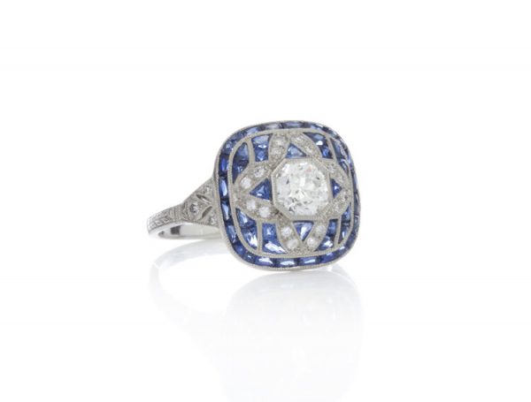 Art Deco Style 0.80ct Sapphire, Diamond and Platinum Cluster Ring; central 0.52ct old-cut diamond surrounded by diamonds and mixed cut sapphires in a geometric star design. Circa 1980s