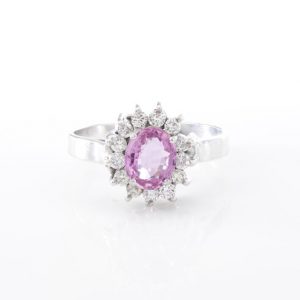 Vintage Pink Sapphire and Diamond Oval Cluster Ring; central 1.00ct oval pink sapphire surrounded by 0.39cts round brilliant-cut diamonds, in 18ct white gold. Circa 1970s