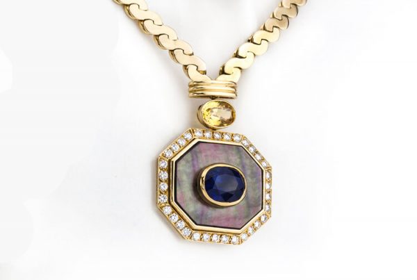 Van Cleef and Arpels Sapphire, Mother of Pearl and Diamond set 18ct Yellow Gold Necklace; octagonal pendant featuring a central 3.00ct oval blue sapphire within a mother-of-pearl frame, bordered by diamonds, suspended via a 1.5ct oval yellow sapphire from a chunky fancy 'S' link chain. Comes in original Van Cleef & Arpels necklace pouch