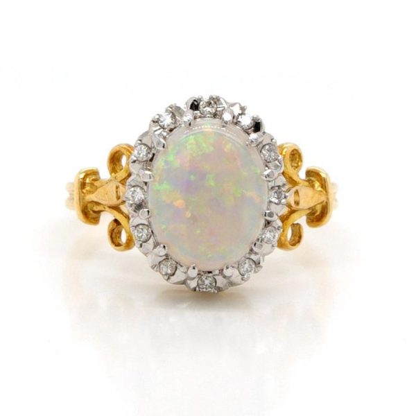 Vintage Opal and Diamond Oval Cluster Ring; featuring a white opal with easily distinguishable flecks in a variety of colours, in 18ct Yellow Gold with scrolled Fleur de Lys shoulders