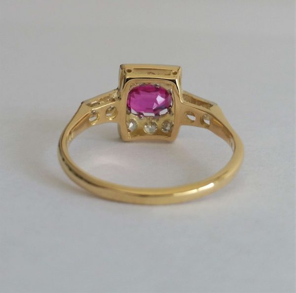 Art Deco Pink Sapphire and Old Cut Diamond Cluster Ring; an oval pink sapphire of intense colour is set in 18ct gold and platinum surrounded by small old cut diamonds. Circa 1920s