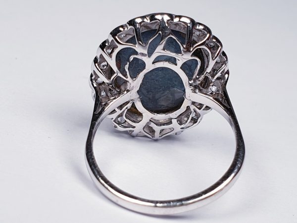 Vintage Cabochon Black Opal and Old Cut Diamond Oval Cluster Dress Ring; featuring a large oval cabochon black opal surrounded by 0.60cts circular old-cut diamonds. Mounted in 18ct white gold. English, Circa 1940s