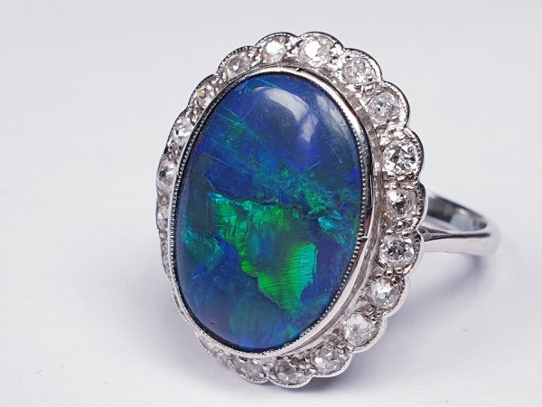 Vintage Black Opal and Old Cut Diamond Oval Cluster Dress Ring; featuring a large oval cabochon black opal surrounded by 0.60cts circular old-cut diamonds. Mounted in 18ct white gold. English, Circa 1940s