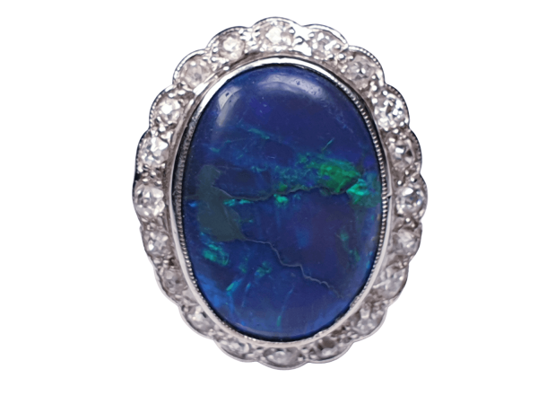 Vintage Black Opal and Old Cut Diamond Oval Cluster Dress Ring; featuring a large oval black opal surrounded by 0.60cts circular old-cut diamonds. Mounted in 18ct white gold. English, Circa 1940s