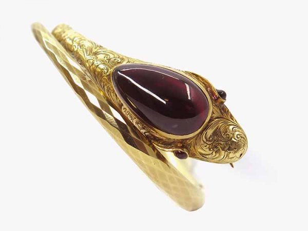 Mid Victorian Serpent snake bangle, the head set with garnet cabochon and garnet eyes, to a tapering hinged bangle.