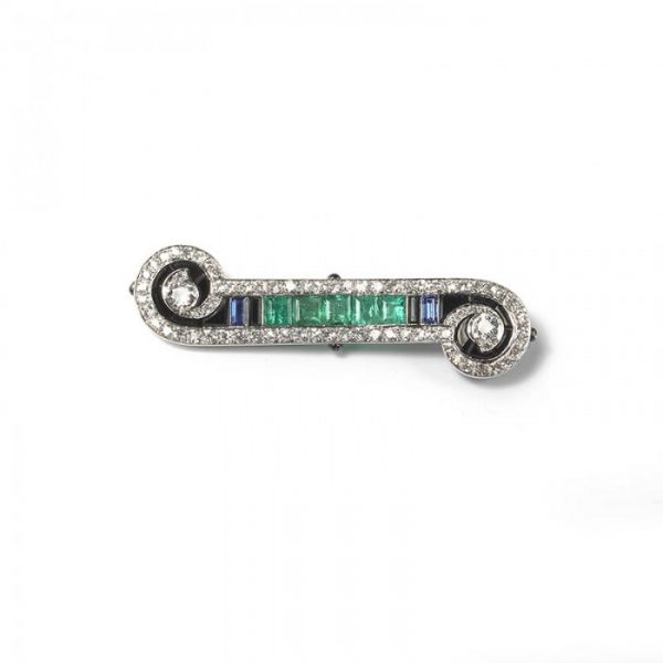 Art Deco French Emerald Sapphire Onyx and Diamond Bar Brooch in Platinum; set with 2.00cts calibre-cut emeralds, 0.50cts calibre-cut sapphires and fancy-cut black onyx, framed by 2.50cts old-cut and single-cut diamonds, in a scroll design, with enamelled detail