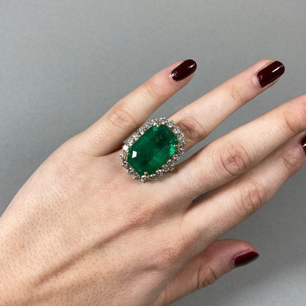 Vintage Colombian Emerald and Diamond Cluster Ring; 21.00 carat emerald-cut emerald surrounded by 2.20 carats of round brilliant-cut diamonds, in 18ct yellow gold, Circa 1980, with a GCS certificate