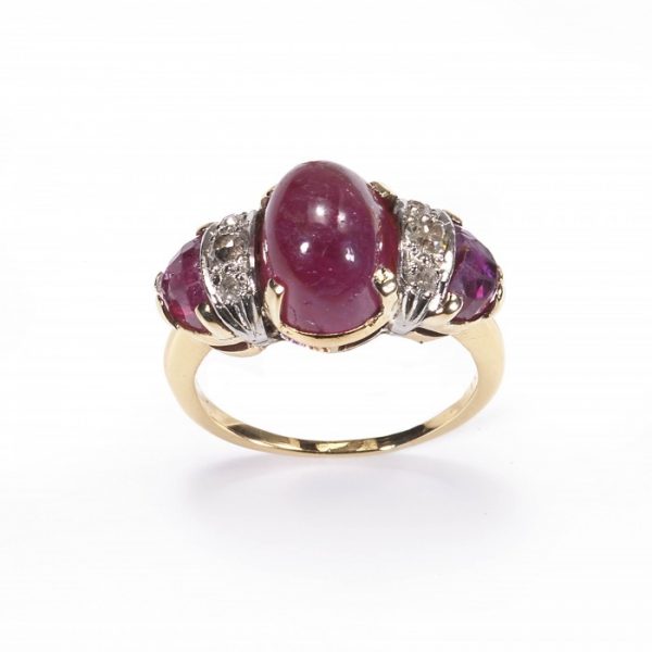 Vintage Cabochon Ruby and Diamond Three Stone Ring; central 4.80 carat cabochon-cut ruby, flanked by fancy faceted rubies and brilliant-cut diamonds, claw set in yellow gold. Circa 1950