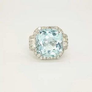 Cushion Cut Aquamarine and Diamond Cluster Ring; central 9.91 carat square cushion aquamarine surrounded by diamonds, with modified square step-cut diamonds to the shoulders, in 18ct white gold