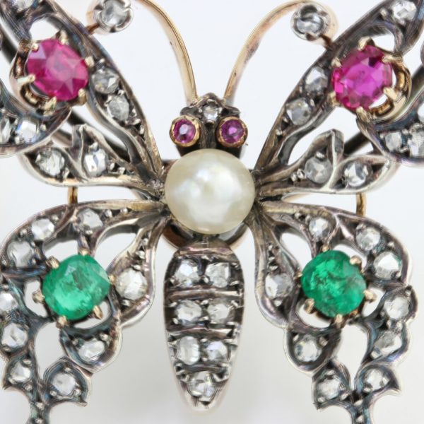 Antique Victorian Multi Gemstone Butterfly Brooch with Natural Pearl; natural freshwater pearl set within a rose-cut diamond encrusted body, accented with blue sapphires, rubies and emeralds. Set in silver and 15ct gold. Made in England, Circa 1860s