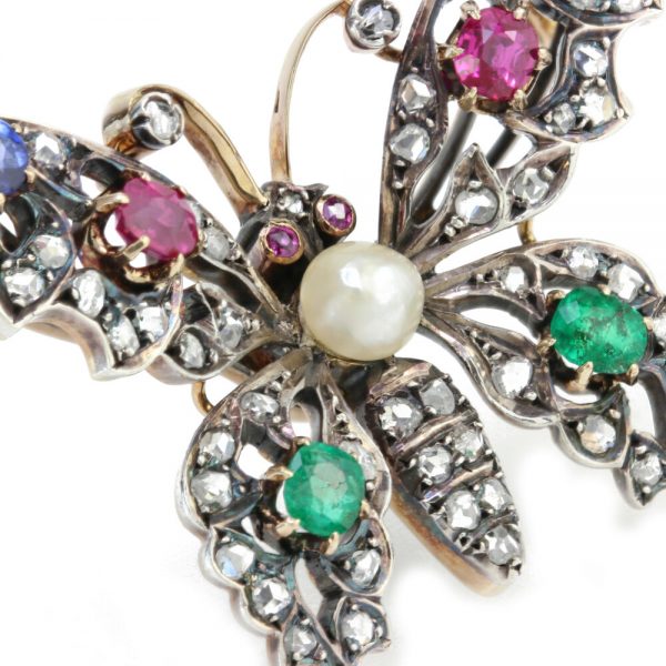 Antique Victorian Multi Gemstone Butterfly Brooch with Natural Pearl; natural freshwater pearl set within a rose-cut diamond encrusted body, accented with blue sapphires, rubies and emeralds. Set in silver and 15ct gold. Made in England, Circa 1860s