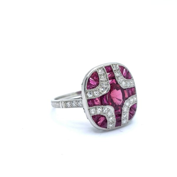 Art Deco Style Ruby and Diamond Cluster Dress Ring in Platinum; central oval faceted ruby surrounded by calibre-cut rubies and brilliant-cut diamonds in a symmetrical geometric pattern