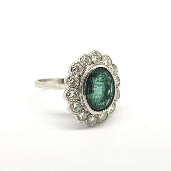 Emerald and Diamond Floral Cluster Ring; central 3.50ct oval faceted emerald within a 1.25ct brilliant-cut diamond surround, in 18ct white gold