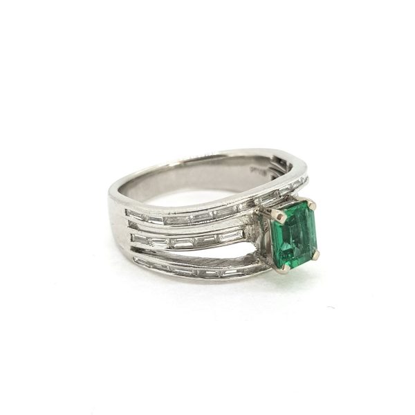 Contemporary Emerald and Diamond Three Band Ring; claw set emerald-cut emerald on three bands channel-set with 0.79cts baguette-cut diamonds, in 18ct white gold