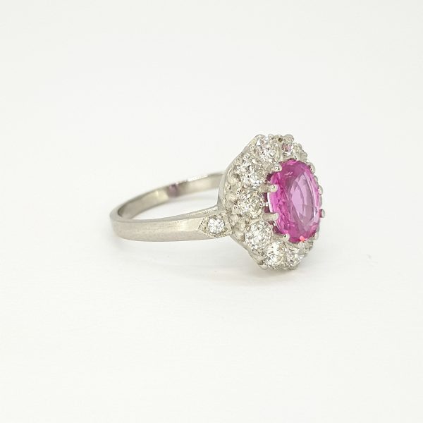 Edwardian Style Pink Sapphire and Diamond Cluster Ring in Platinum; 1.40ct oval pink sapphire surrounded by ten sparkling brilliant-cut diamonds, 1.00 carat diamonds