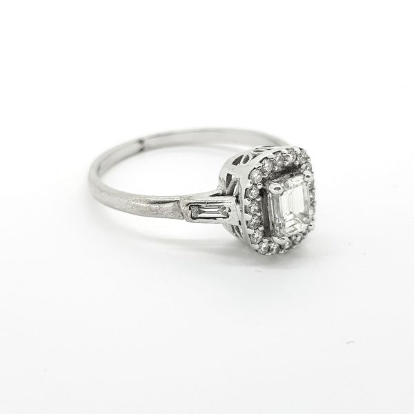 Emerald Cut Diamond Halo Cluster Ring; central 0.52 carat emerald-cut diamond surrounded by a halo of brilliant-cut diamonds, with baguette-cut diamond-set shoulders, in 18ct white gold