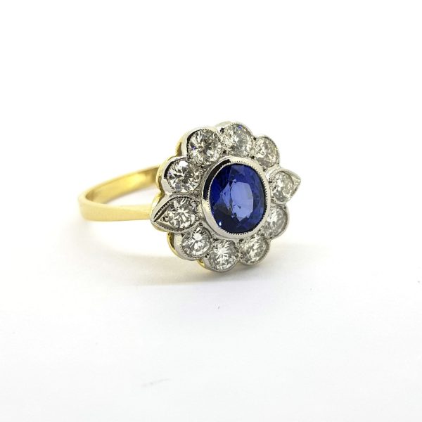Sapphire and Diamond Floral Cluster Ring; central 0.90 carat sapphire set within a 1.20ct diamond surround, platinum and 18ct yellow gold shank