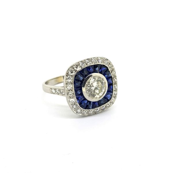 Sapphire and Diamond Cluster Target Ring; 0.84ct brilliant-cut diamond surrounded by French cut sapphires and outer border of diamonds, 18ct white gold