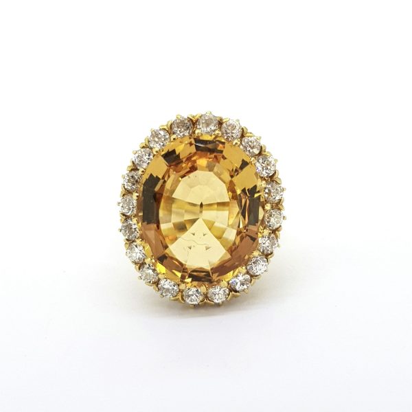 Vintage Imperial Topaz and Diamond Cluster Ring; oval-cut Imperial topaz encircled by old-cut diamonds, in yellow gold with fleur de lis shoulders, Circa 1970s