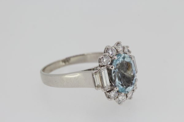 Aquamarine and Diamond Oval Cluster Ring; central 2.00ct oval faceted aquamarine bordered by brilliant cut diamonds, graduated baguette-cut diamond set shoulders, in 18ct white gold