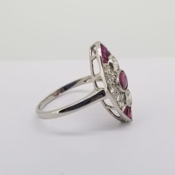 Ruby and Diamond Marquise Shaped Cluster Navette Ring in Platinum; central oval-cut ruby has a round brilliant-cut diamond set above and below within a diamond-set cluster surround, calibre cut rubies set to the tips