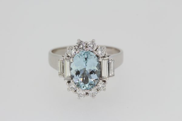 Aquamarine and Diamond Oval Cluster Ring; central 2.00ct oval faceted aquamarine bordered by brilliant cut diamonds, graduated baguette-cut diamond set shoulders, in 18ct white gold