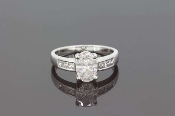 Oval Cut Diamond Engagement Ring; featuring a 1.22 carat oval-cut diamond, claw set, and accented with diamond set shoulders, in 18ct white gold
