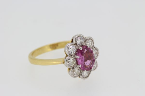 Pink Sapphire and Diamond Floral Cluster Ring; 1.25ct oval pink sapphire surrounded by eight round brilliant-cut diamonds, in 18ct white gold to a 18ct yellow gold band