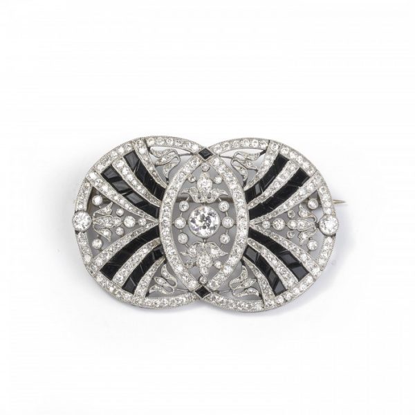 Belle Epoque Old Cut Diamond, Onyx and Platinum Brooch; designed as two concentric circles set with fancy cut black onyx and round old-cut diamonds, in a platinum openwork frame, with millegrain edges. Circa 1900.
