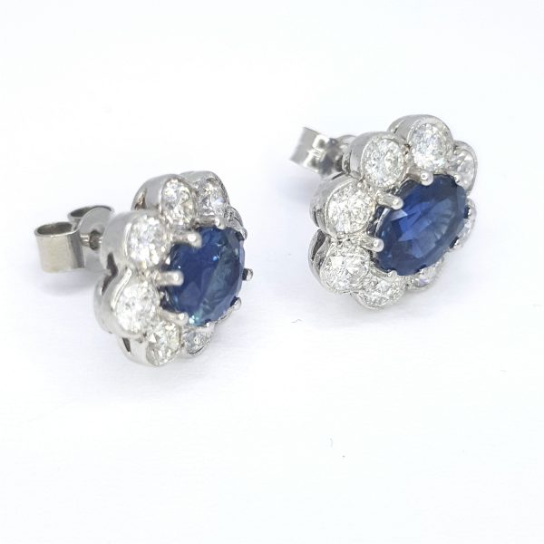 Oval Cut Sapphire and Diamond Floral Cluster Stud Earrings; 2.13cts oval sapphires surrounded by 1.35cts of diamonds, in 18ct white gold