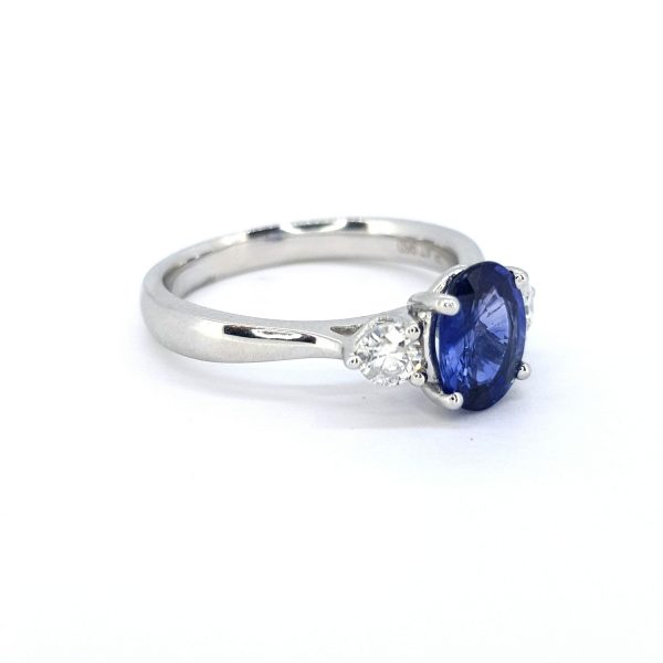 Sapphire and Diamond Three Stone Ring in Platinum; central 1.41ct oval Madagascan sapphire flanked by 0.30cts sparkling white G colour round brilliant-cut diamonds