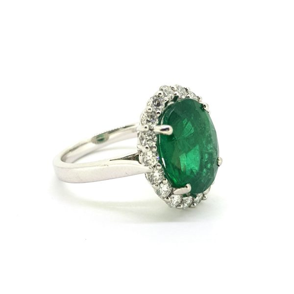 Emerald and Diamond Oval Cluster Ring in Platinum; central 4.53ct oval Zambian emerald is claw set within a halo of 18 brilliant cut diamonds, in platinum