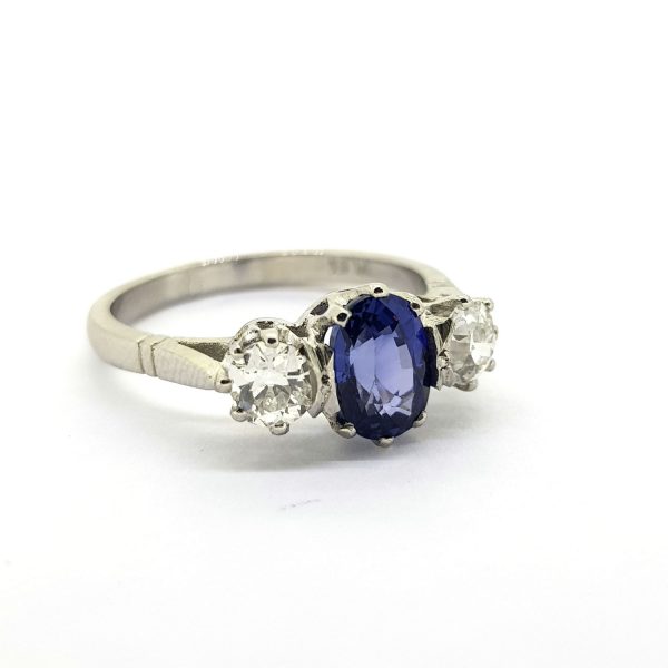 Oval Cut Sapphire and Diamond Three Stone Ring in Platinum; central 1.00ct oval faceted sapphire flanked by 0.60cts sparkling diamonds