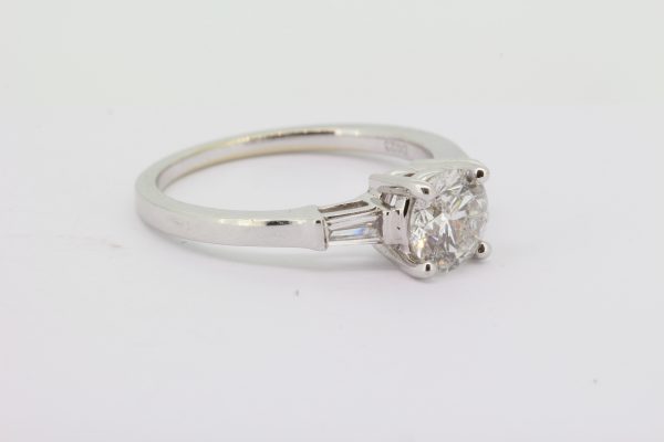 Diamond Solitaire Engagement Ring with Baguette Shoulders; central 0.98ct round brilliant-cut diamond, four claw set, and flanked by collet set tapered baguette-cut diamonds to the shoulders, in 18ct white gold