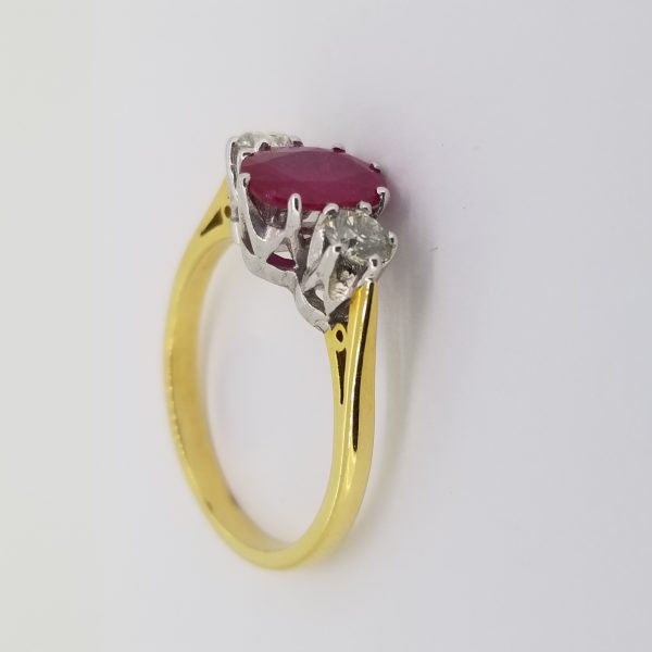 Ruby and Diamond Three Stone Ring; central oval faceted ruby flanked by brilliant-cut diamonds, in 18ct yellow gold