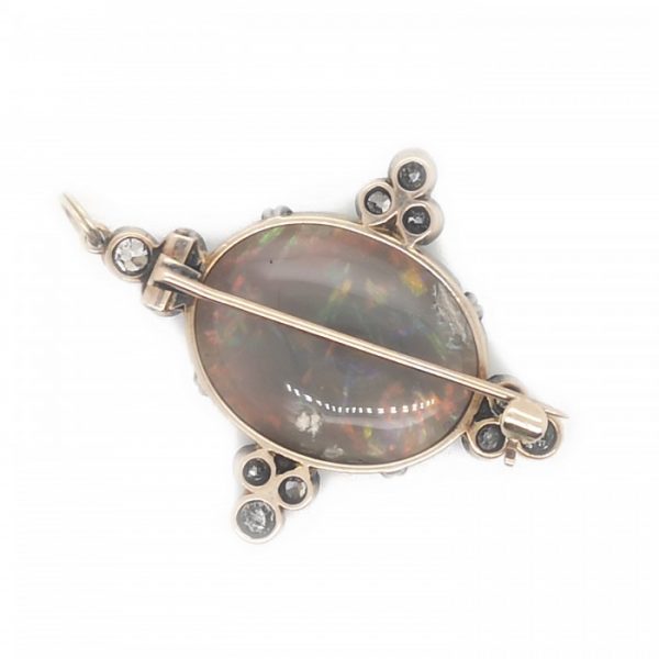 Antique Opal and Diamond Pendant Brooch; claw set oval cabochon-cut opal, with predominantly red play of colour, accented with four groups of three old-cut diamonds set in a trefoil design, in silver and gold. Circa 1900