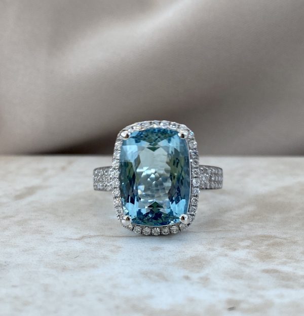 Aquamarine and Diamond Dress Ring; 6.21ct cushion-shaped oval faceted aquamarine with diamond surround and three rows of diamonds to each shoulder, in 18ct white gold with pierced heart detail to under-gallery