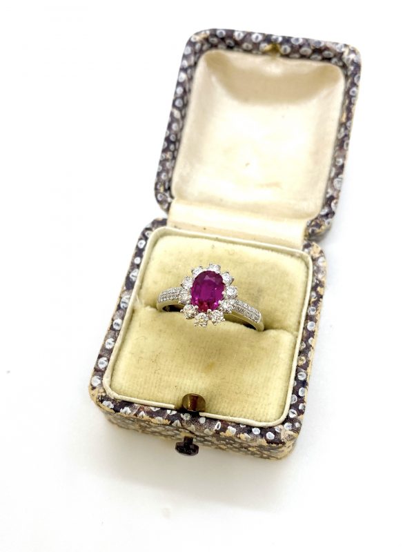 Burma Ruby and Diamond Cluster Ring in Platinum; 1.16 carat oval faceted Burmese ruby claw set within a diamond surround, with two rows of diamonds set into each shoulder