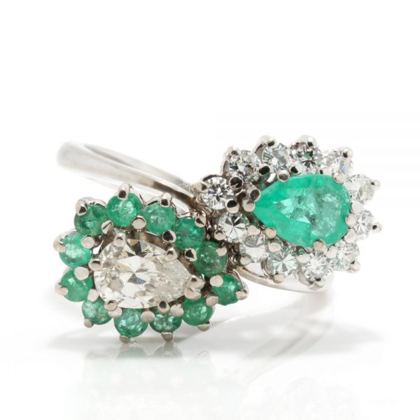Vintage Emerald and Diamond Cluster Crossover Ring; One cluster comprises of a pear-cut diamond surrounded by round-cut emerald, the other of a pear cut emerald within a brilliant-cut diamond surround, in 18ct white gold, Circa 1950s-1970s