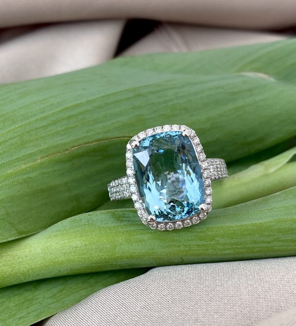 Aquamarine and Diamond Dress Ring; 6.21ct cushion-shaped oval faceted aquamarine with diamond surround and three rows of diamonds to each shoulder, in 18ct white gold with pierced heart detail to under-gallery