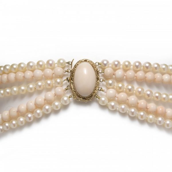 Vintage Coral and Cultured Pearl Five Row Necklace; comprised of three rows of 6mm white cultured pearls and two rows of 8mm round coral beads, a cabochon coral clasp, in 18ct yellow gold, Circa 1970