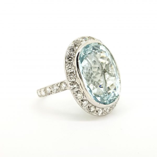 Aquamarine and Diamond Oval Cluster Ring; large 22.00 carat oval aquamarine within a frame of brilliant cut diamonds and diamond set band, in 18ct white gold with unusual under-bezel