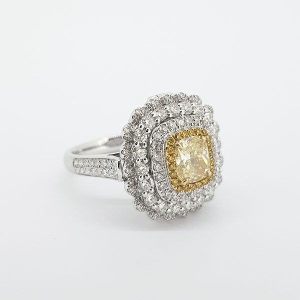 Yellow and White Diamond Cluster Ring; central GIA certified 1.00 carat cushion-shaped yellow diamond, surrounded by a halo of yellow diamonds and three further halos of sparkling white diamonds, in 18ct white gold