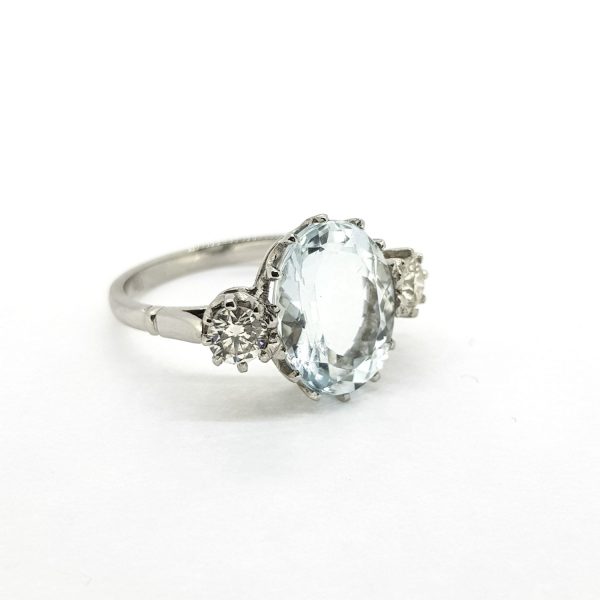 Oval Cut Aquamarine and Diamond Three Stone Ring in Platinum; central 4.50 carat oval aquamarine flanked by 0.55cts diamonds