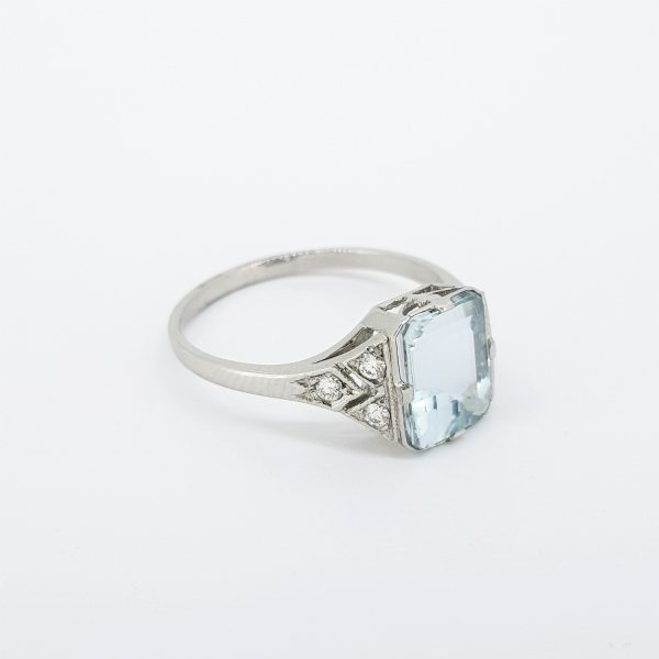 Aquamarine and Diamond Cluster Dress Ring in Platinum; central 2.15 carat emerald-cut aquamarine, claw set, flanked by three diamonds to each shoulder, pave-set in kite formation
