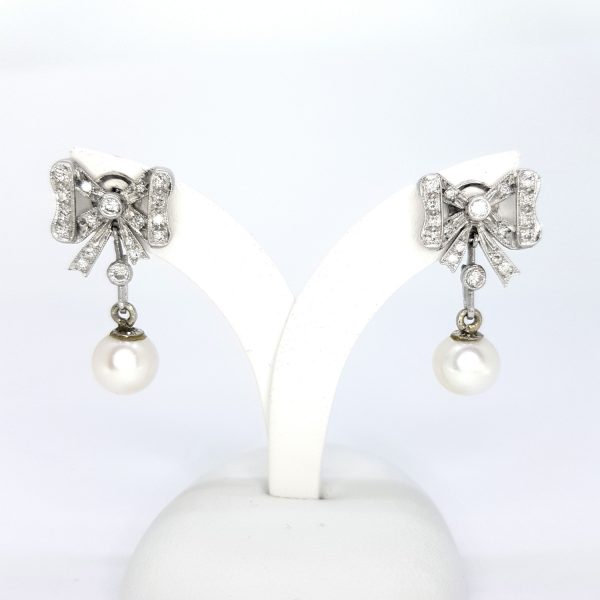 Vintage Pearl and Diamond Bow Drop Earrings; in the Belle Epoque style, silky white pearls suspended from diamond-set bows, in 18ct white gold