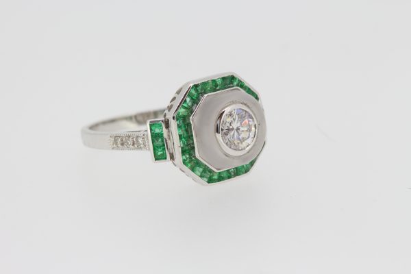 Diamond, Crystal and Emerald Cluster Target Ring; central 0.60ct diamond within a crystal surround, all bordered by calibre-cut emeralds, in 18ct white gold