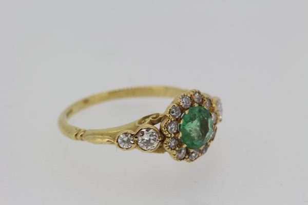 Georgian Style Emerald and Old Cut Diamond Cluster Ring; circular emerald surrounded by old-cut diamonds, diamond set shoulders, in 18ct yellow gold